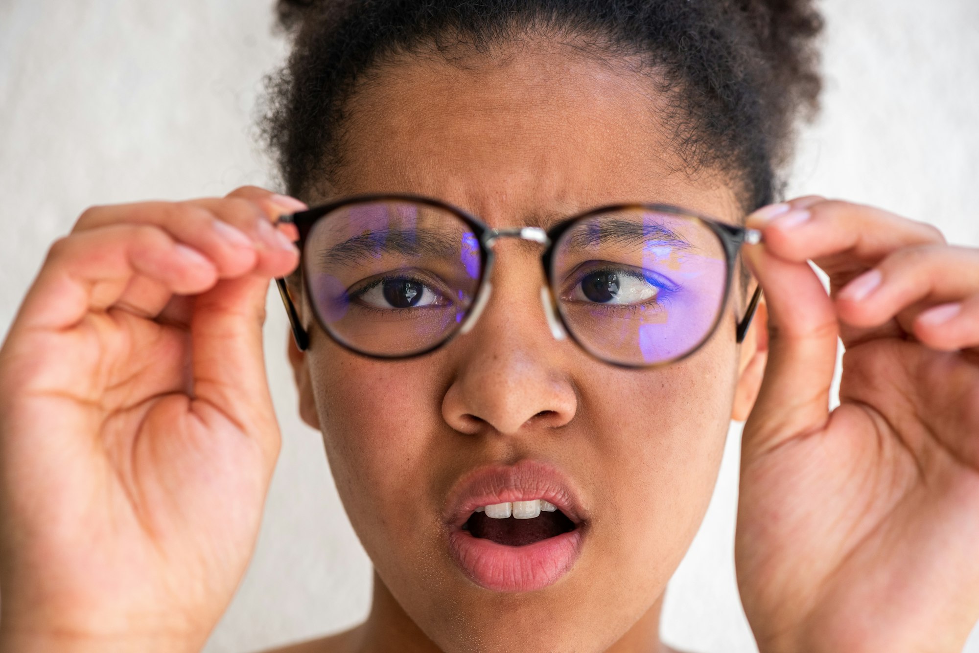 Close up girl holding eyeglasses with confused expression on face