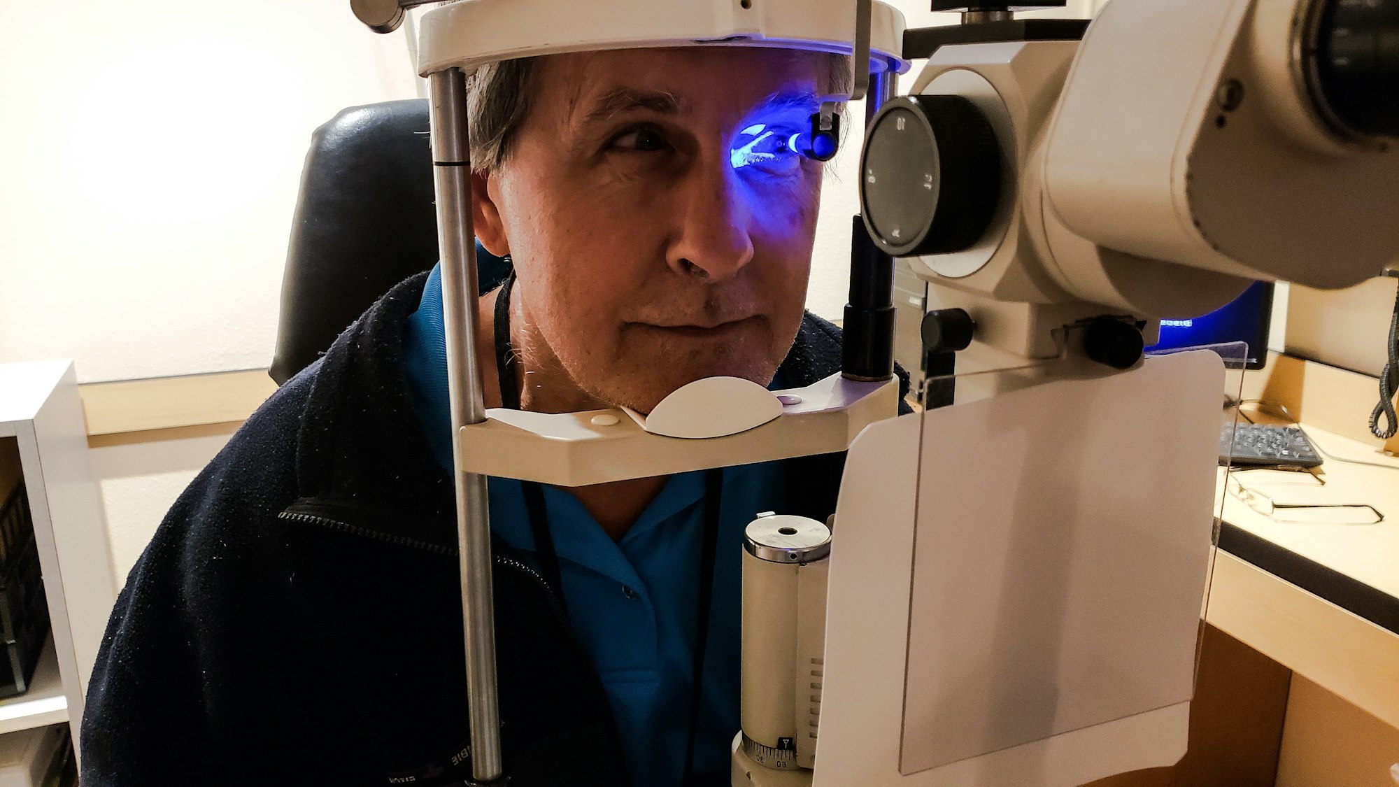Spotlight on yearly eye exam for babyboomer by ophthalmologist to check for glaucoma with neon light