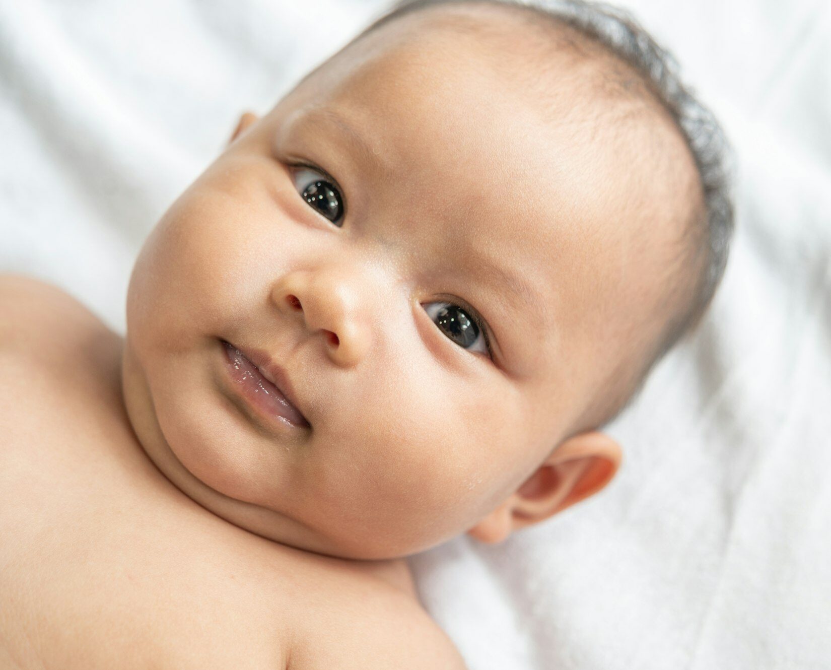 A newborn baby who opens his eyes and looks forward